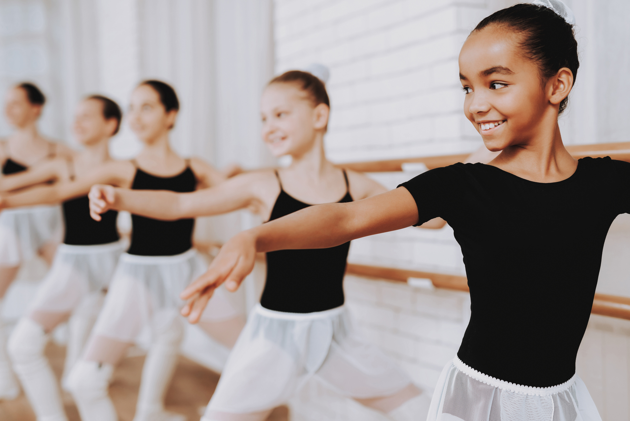A group of young girls training together in a ballet studio
