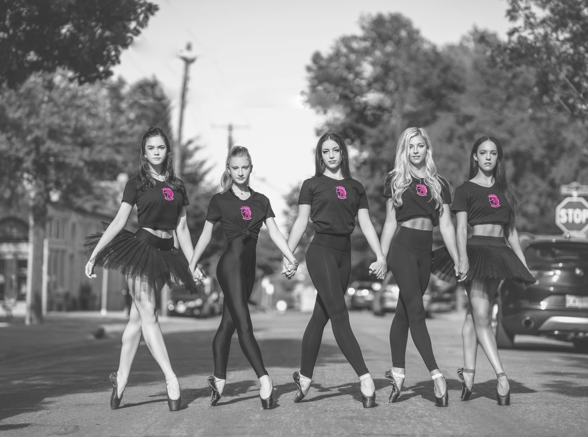 Five scholarship recipients holding hands across a street, on pointe